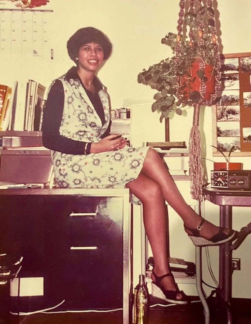 Young Sylvia posing, sitting on a desk